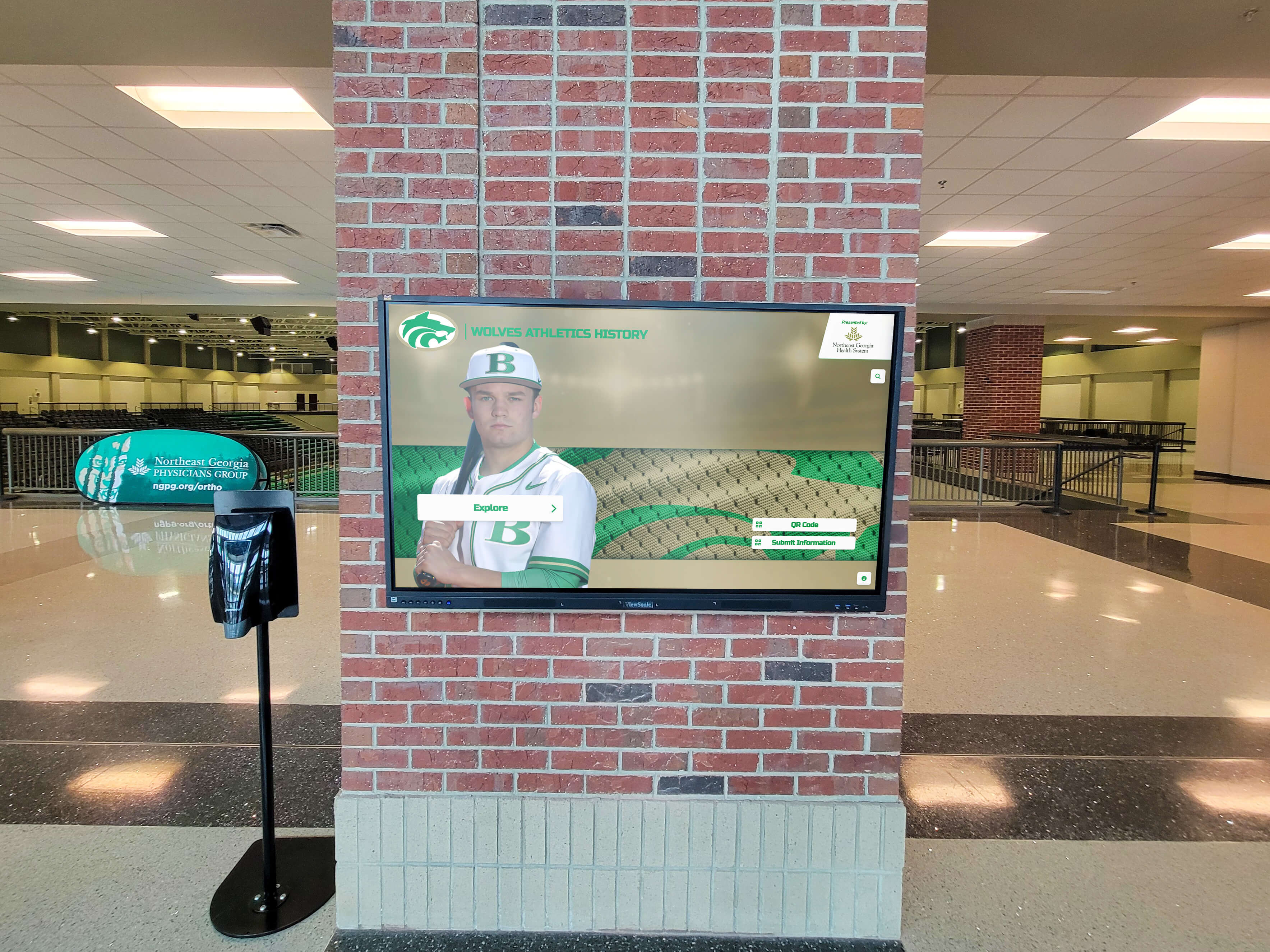 Digital display showing baseball player on brick pillar in athletic facility lobby Digital display in athletic facility