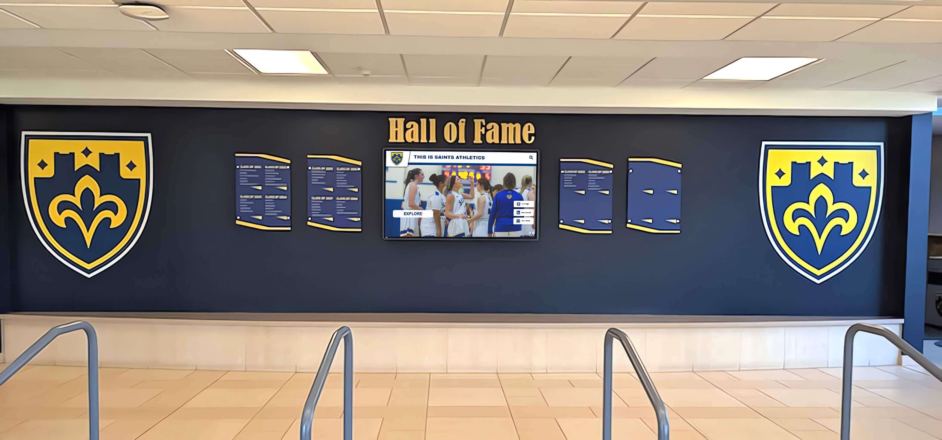 School lobby hall of fame wall featuring shield displays and integrated digital screen Hall of fame wall display